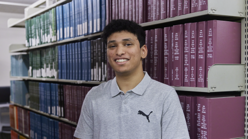 Saarim Rizavi in front of a bookshelf in the library