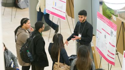 A student presenting a research poster at the Annual Undergraduate Research Symposium