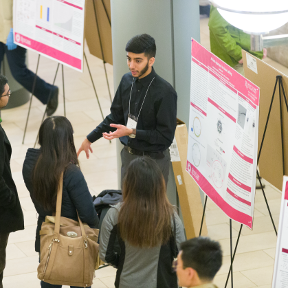 A student presenting a research poster at the Annual Undergraduate Research Symposium