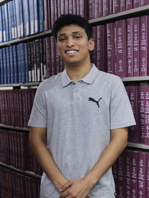 Saarim Rizavi in front of a bookshelf in the library