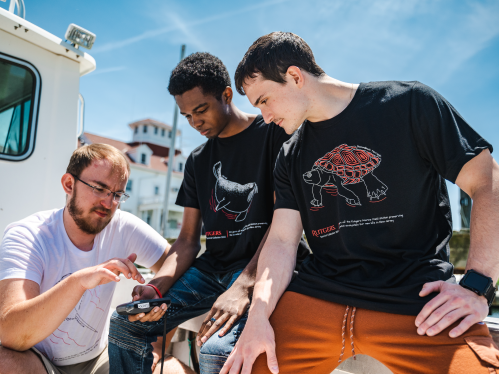Rutgers Marine Field Station laboratory technician Douglas Hood (left) shows Jamin Brako (SOE '25; center) and Salvatore Fricano (SEBS '23) how to use equipment on the research boat.