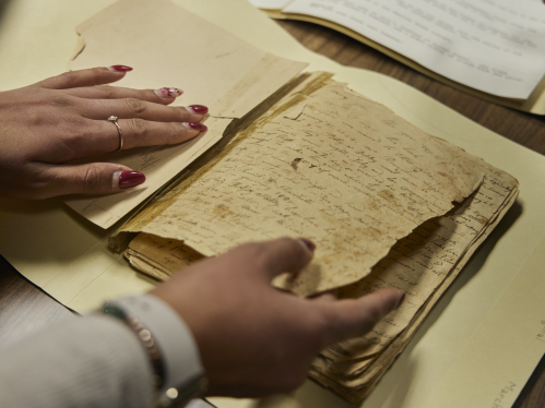 A student turning the pages of an old manuscript