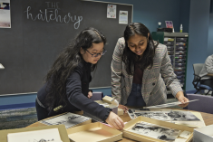 A student looking through Special Collections archives with a staff member in The Hatchery