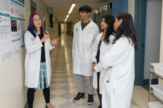 A faculty mentor Annika Barber discussing a research poster with three students