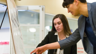 Annual symposium presenter with her poster presenting to a guest.